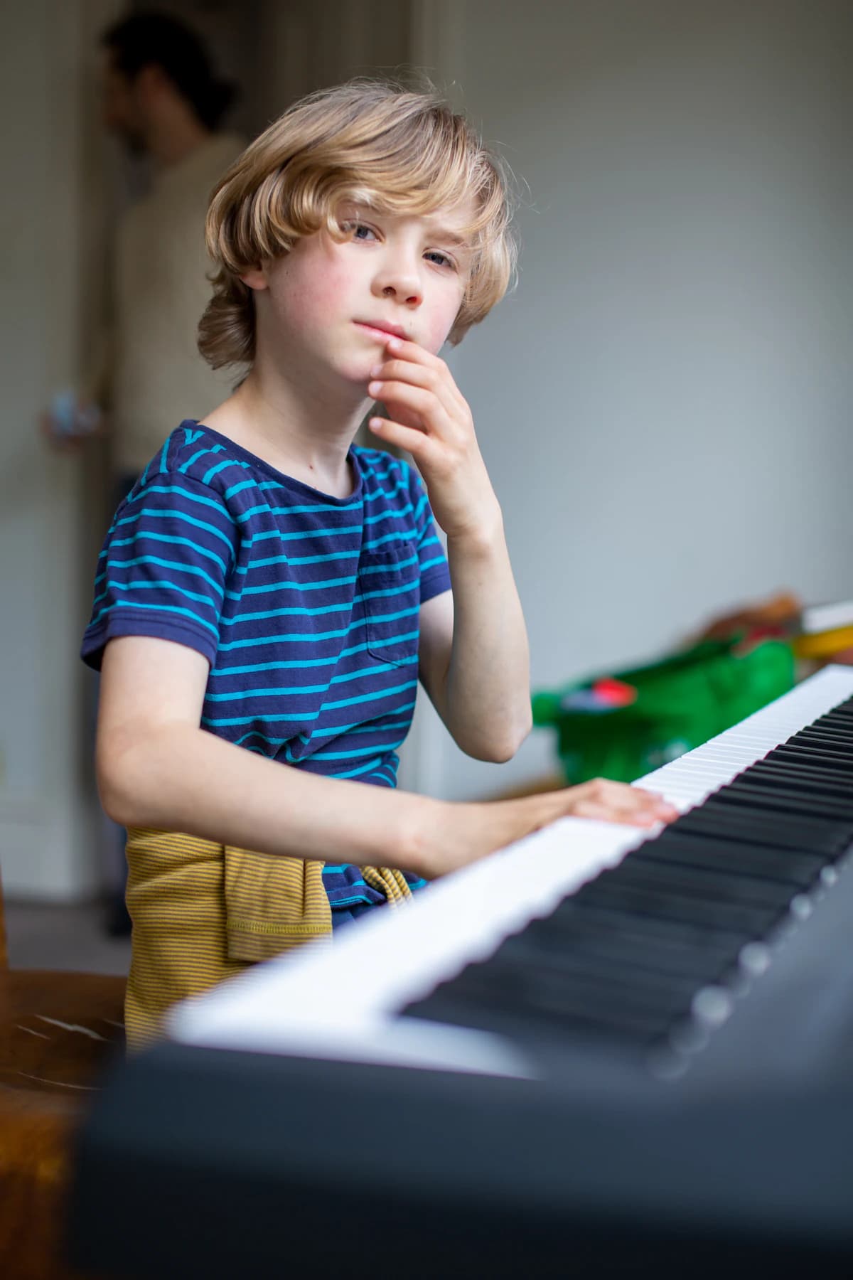 Boy pausing to think while practising on a keyboard
