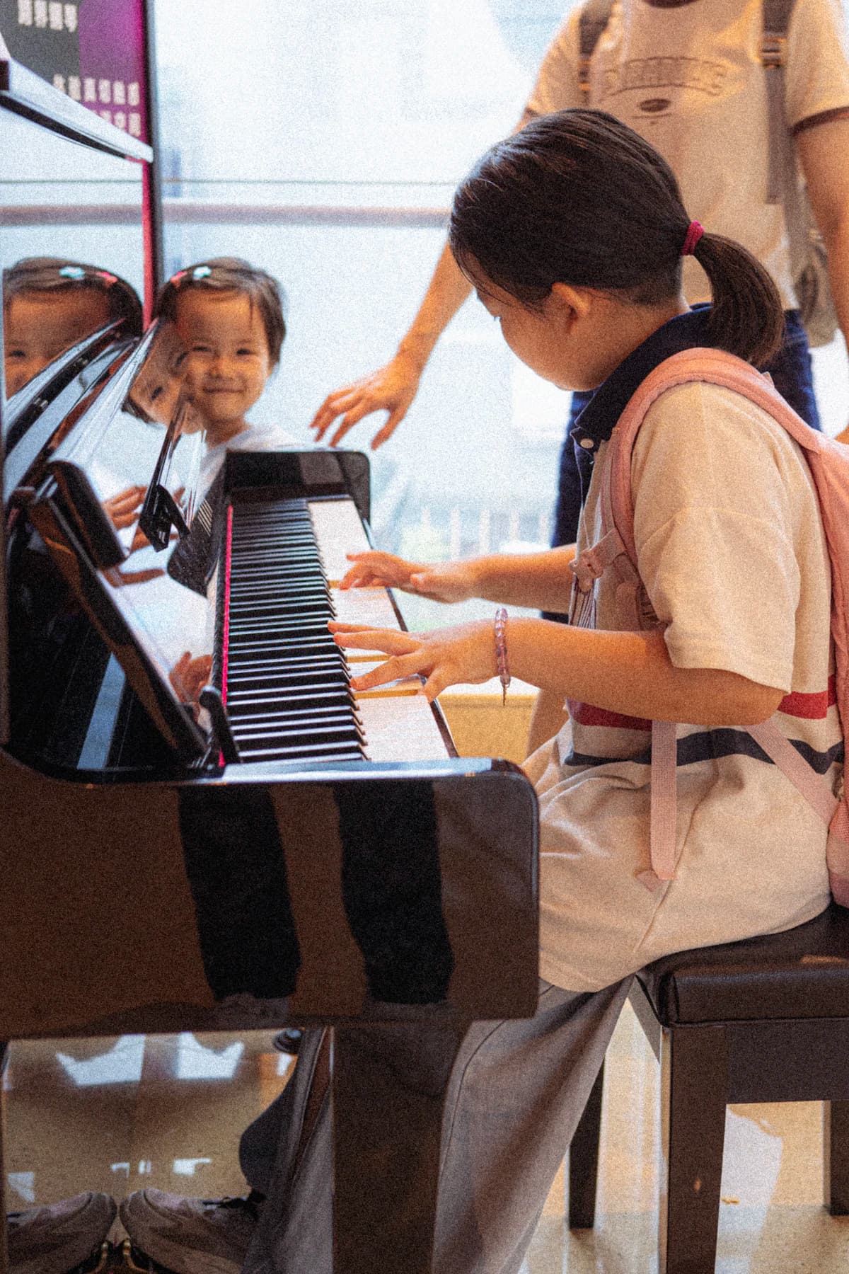 Children gathered around a piano in a classroom