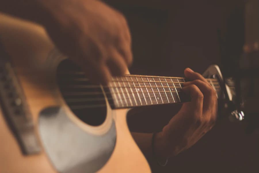 Guitarist fretting a chord on an acoustic guitar