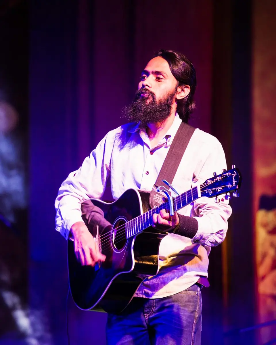 Vivek Badoni playing an acoustic guitar on stage
