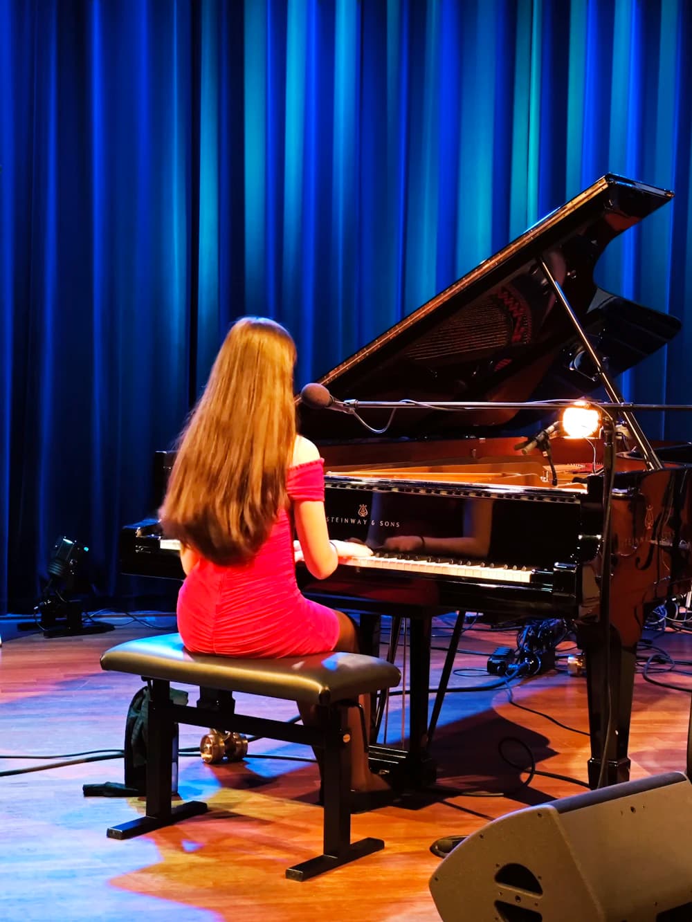 Girl performing on a grand piano on a lit stage
